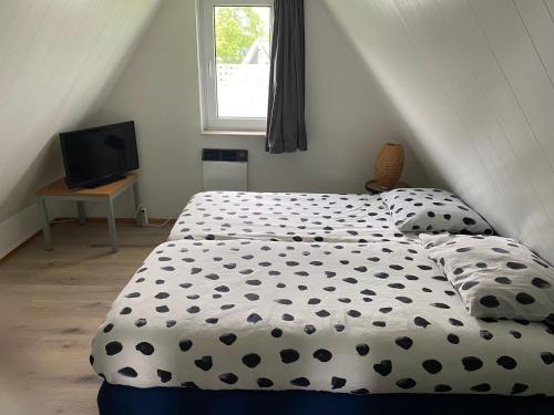a bedroom with a bed with a black and white comforter at Vijverzicht 221 met whirlpool in Gramsbergen