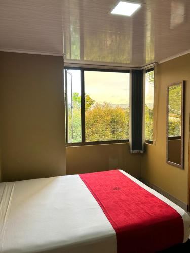 a bedroom with a large bed with a red blanket at Hotel Campo Real in Rionegro