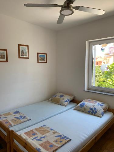 two twin beds in a room with a window at Apartment Sun in Novalja