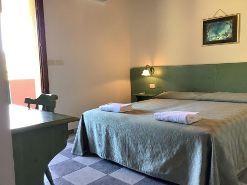una camera con letto, tavolo e scrivania di Hotel Golfo del Leone a Portixeddu