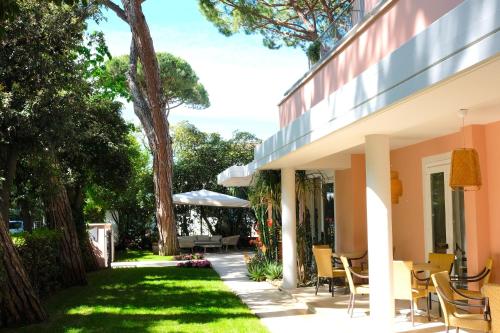 um pátio de uma casa com cadeiras e árvores em Hotel Piccolo Mondo em Lido di Camaiore