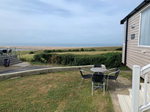 a patio with a table and chairs on the side of a house at B1 - Pebble Bank Caravan Park in Weymouth