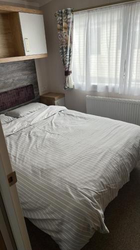 1 cama blanca en un dormitorio con ventana en B1 - Pebble Bank Caravan Park, en Weymouth