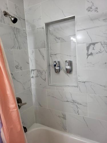 a white bathroom with a tub and a mirror at Seeing Busch Gardens from two apartments in Tampa