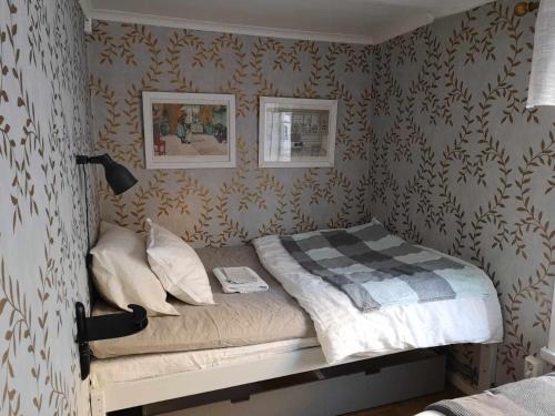a small bed in a bedroom with wallpaper at Kopparstugans Bed & Breakfast in Falun
