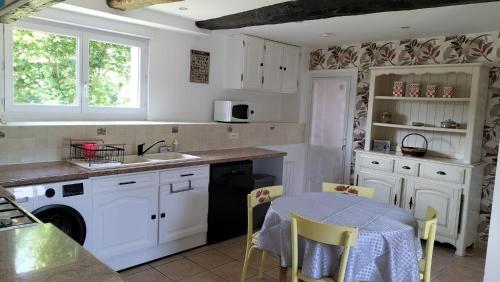 - une cuisine avec des placards blancs, un évier et une table dans l'établissement Gîte Au Cerisier, à Plouégat-Guérand