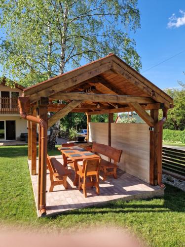 a wooden pavilion with a picnic table and benches at Bánki Vendégház in Bánk