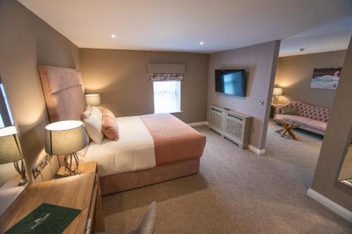 Castle Varagh Hotel & Bar في ويستميث: غرفة نوم بسرير وتلفزيون وأريكة