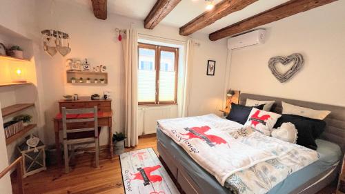 um quarto com uma cama, uma secretária e uma janela em GITE LE COQ ROUGE em Eguisheim