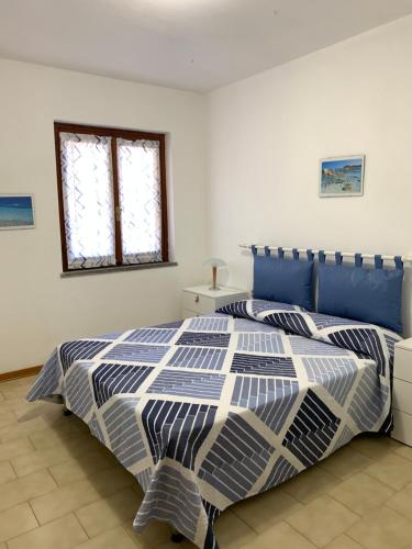 Un dormitorio con una cama azul y blanca y una ventana en A pochi passi dal mare, con giardino privato - A few meters from the sea, with private garden en Stintino