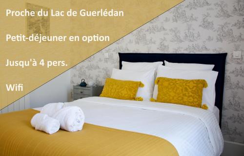 een slaapkamer met een bed met gele en witte kussens bij Valfrescos - Lac de Guerlédan in Caurel