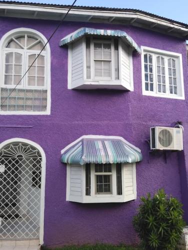 a purple building with two windows and a awning at Queste Ochi Town House in Ocho Rios
