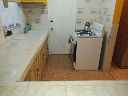 a kitchen with a stove top oven next to a sink at Queste Ochi Town House in Ocho Rios
