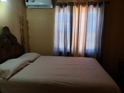 a bed in a bedroom with curtains and a bed sidx sidx sidx at Queste Ochi Town House in Ocho Rios