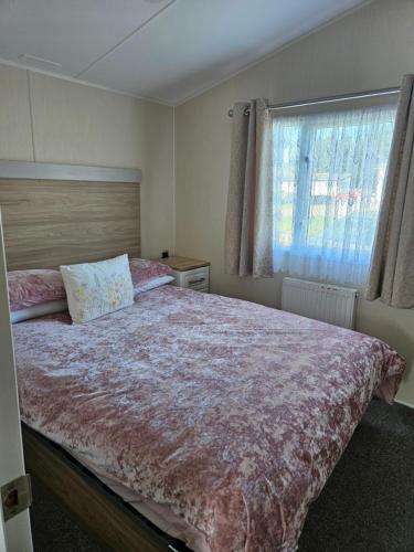 een slaapkamer met een groot bed en een raam bij Jenny,s place in Saint Osyth