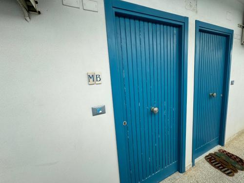 two blue doors on the side of a building at A Window to the Sea in Nettuno