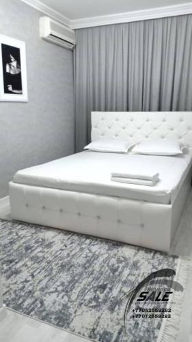 ein weißes Bett in einem Schlafzimmer mit einem Teppich in der Unterkunft Элитная 2-комнатная квартира в районе Болашак in Kooperator