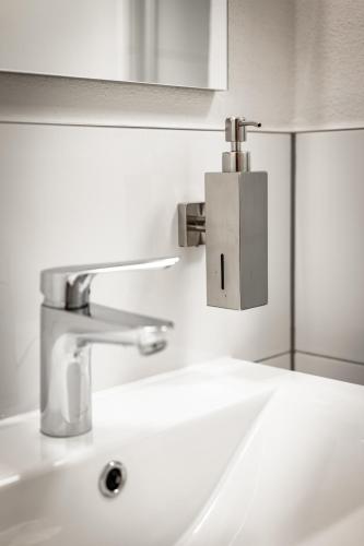 a bathroom sink with a silver faucet on the wall at Rennglück Apartments in Kelberg