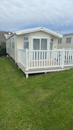 a house with a white porch and a white fence at T23- Pebble Bank Caravan Park in Weymouth