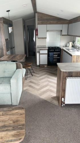 a living room with a couch and a kitchen at T23- Pebble Bank Caravan Park in Weymouth