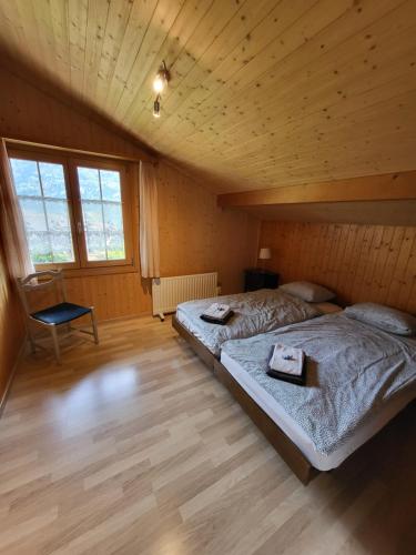ein Schlafzimmer mit 2 Betten und einem Stuhl darin in der Unterkunft Zauberhaftes Chalet mit Whirlpool, Berg & Seesicht in Brienz