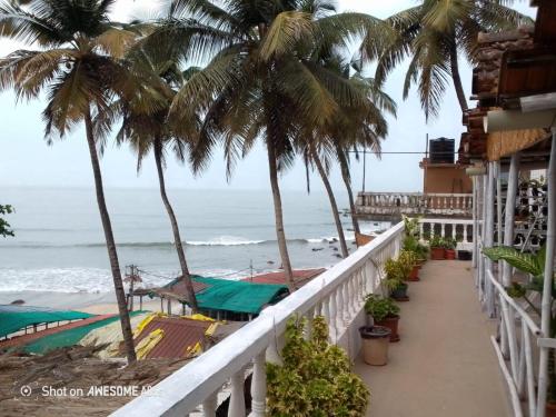 a balcony with palm trees and the ocean at This is it Beachfront - Rooms, Cafe & Events in Arambol