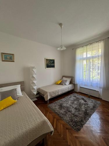 a bedroom with two beds and a window with a rug at Villa Arancia in Dubrovnik
