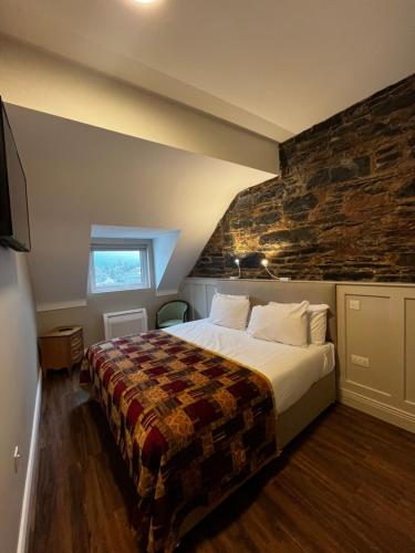 a bedroom with a bed and a stone wall at Donegal House in Donegal