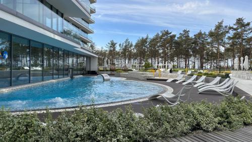 a pool with lounge chairs next to a building at Crest View 777th - Apartament & SPA in Międzyzdroje
