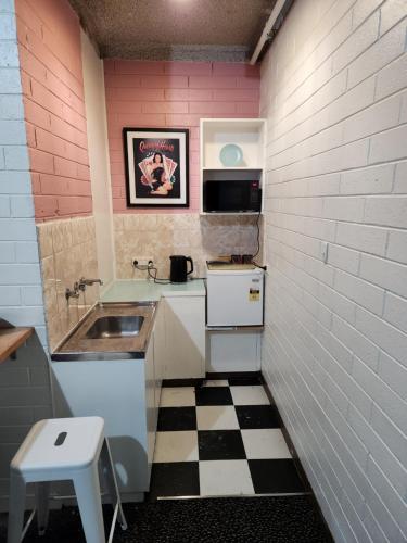 una pequeña cocina con fregadero y suelo a cuadros en West End Motel en Adelaida