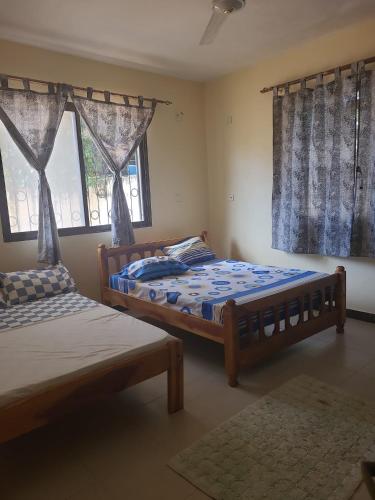a bedroom with two beds and two windows at Picho two bedroom apartment in Malindi