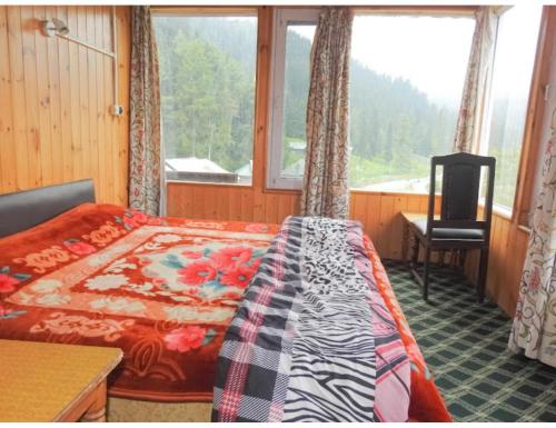 een slaapkamer met een bed, een bureau en een raam bij Hotel Yemberzal & Restaurant, Jammu and Kashmir in Gulmarg