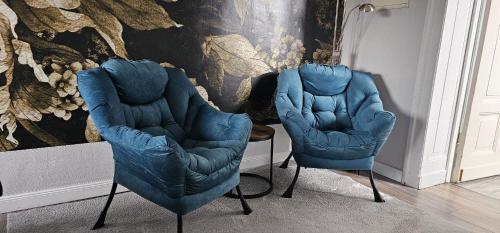 twee blauwe stoelen in een kamer met een muur bij Pension Zur Alten Post in Havelberg