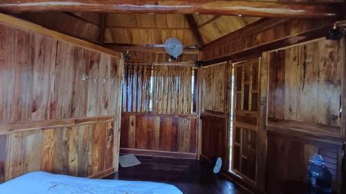 Homestay Highland Hmong في Hòa Bình: غرفة بجدران خشبية وسرير في كابينة