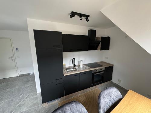una cocina con armarios negros y fregadero en Stilvolles City-Studio en Neuss