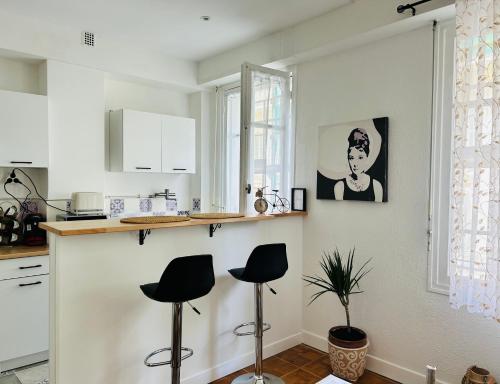une cuisine avec deux tabourets dans une cuisine aux murs blancs dans l'établissement Studio calme Nice hyper centre, à Nice