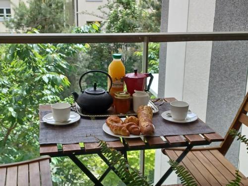 une table avec une bouilloire et des croissants sur un balcon dans l'établissement chez Maria, à Vanves