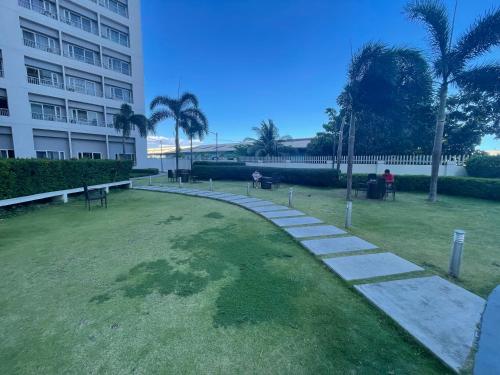 einen Park vor einem Gebäude mit Palmen in der Unterkunft Grace Residences Pool View Free Wi-Fi near BGC and McKinley 2050 in Manila