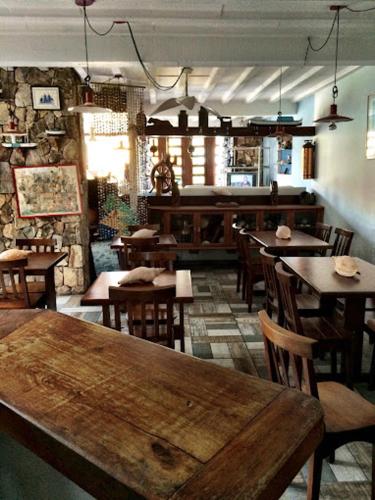 a restaurant with wooden tables and chairs in a room at Pousada do Capitão in Arraial do Cabo