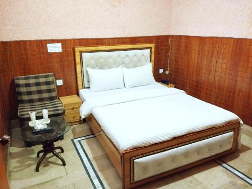 a bedroom with a bed and a chair and a table at Karachi Motel Guest House in Karachi
