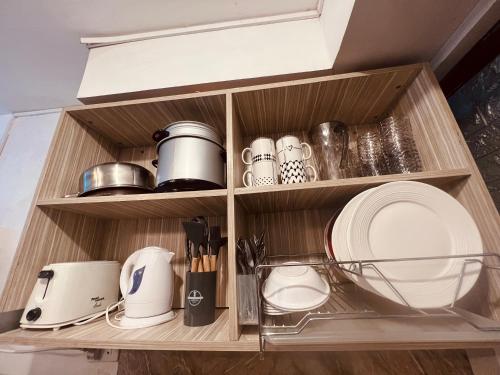 a shelf with dishes and utensils in a kitchen at Mamby Gray's Place Balcony, Karaoke ,Wifi,Netflix &Kitchen in Imus