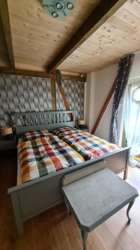 Bett mit einer Decke und einer Bank in einem Zimmer in der Unterkunft Pension und Gästehaus Paffrath in Großbrembach