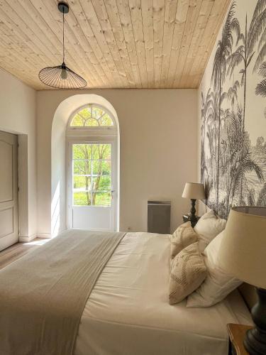une chambre avec un grand lit blanc avec une fenêtre dans l'établissement Gîte de l'orangerie du Château de la Bégude de Mazenc, à La Bégude-de-Mazenc