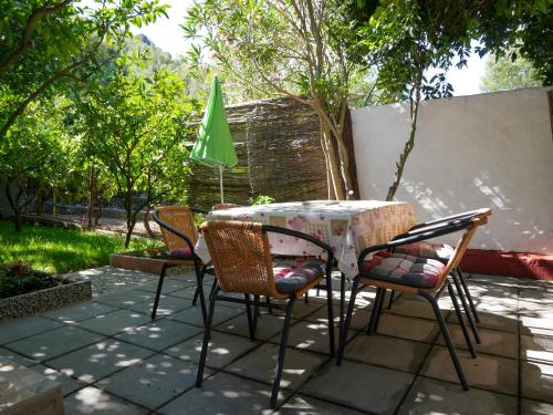 una mesa de patio y sillas con una sombrilla verde en Studio Apartment Maršić en Zaostrog