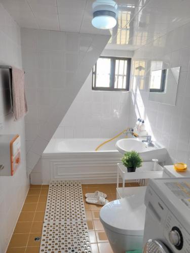 a bathroom with a tub and a toilet and a sink at Como Green House in Busan