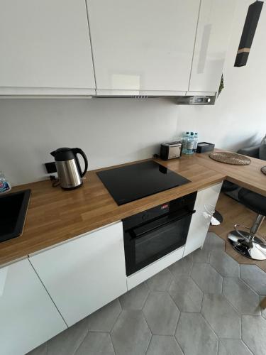 a kitchen with white cabinets and a wooden counter top at APARTAMENT DĄBSKA 24 TAURON ARENA in Kraków