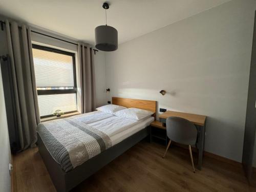 a bedroom with a bed and a desk and a window at APARTAMENT DĄBSKA 24 TAURON ARENA in Krakow