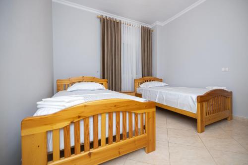 two twin beds in a room with white walls at Adams Apartment in Vlorë