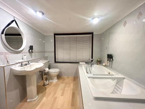 La salle de bains est pourvue d'une baignoire, d'un lavabo et de toilettes. dans l'établissement Duchess House 2- Spacious & Elegant 3BR 1F, à Colchester