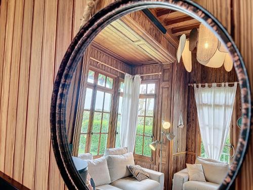 espejo en una habitación con sofá y ventana en La Barbotine, maison normande au pied de la plage, en Villers-sur-Mer